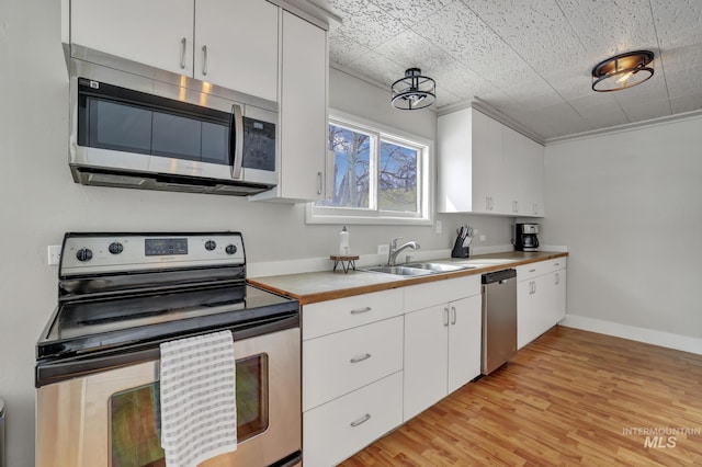 kitchen with a sink, white cabinetry, stainless steel appliances, light wood-style floors, and light countertops