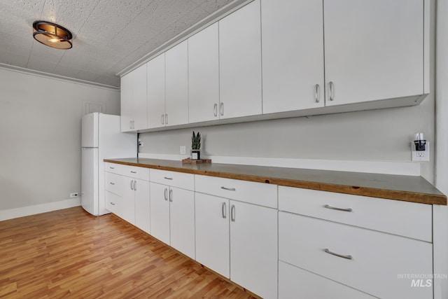 kitchen featuring dark countertops, white cabinets, light wood-style floors, and freestanding refrigerator