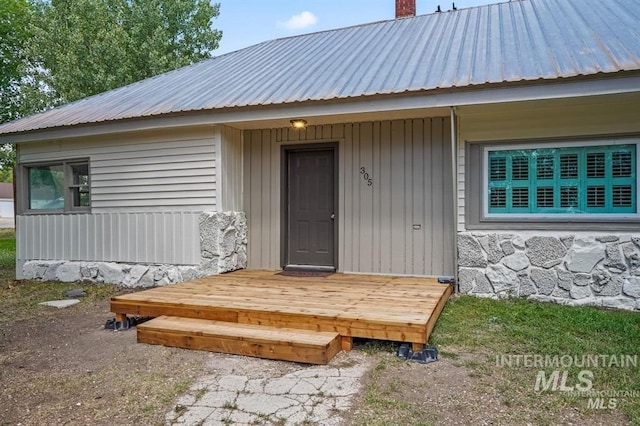 doorway to property featuring a chimney and metal roof