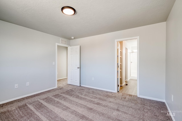 1468 N Coltsfoot Ave, Kuna, ID 83634 - unfurnished bedroom featuring carpet floors, baseboards, a textured ceiling, and connected bathroom