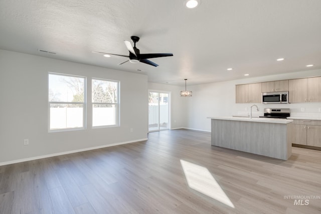 1468 N Coltsfoot Ave, Kuna, ID 83634 - kitchen featuring appliances with stainless steel finishes, light brown cabinets, open floor plan, light countertops, and a kitchen island with sink