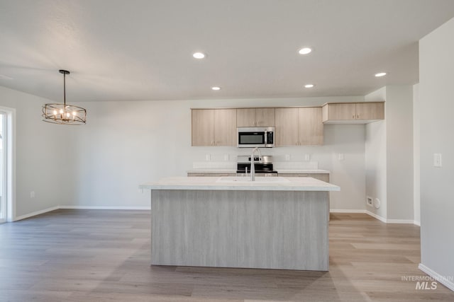 1468 N Coltsfoot Ave, Kuna, ID 83634 - kitchen featuring stainless steel appliances, light countertops, light brown cabinetry, baseboards, and a center island with sink