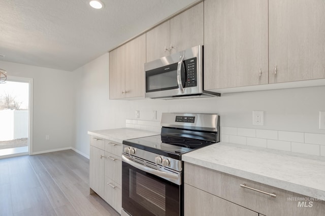 1468 N Coltsfoot Ave, Kuna, ID 83634 - kitchen with stainless steel appliances, light countertops, light wood-type flooring, light brown cabinets, and recessed lighting