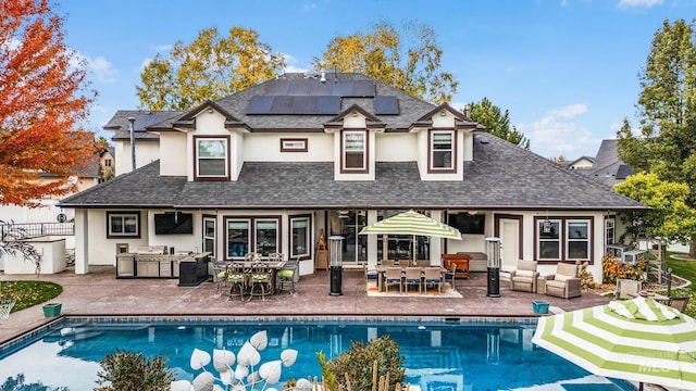 rear view of property with solar panels, a patio area, an outdoor living space, and exterior kitchen