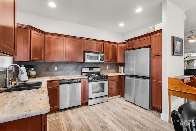 3136 S Bear Claw Way, Meridian, ID 83642 - kitchen with stainless steel appliances, a sink, light wood-type flooring, light stone counters, and decorative backsplash