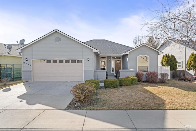 ranch-style house featuring driveway, a shingled roof, an attached garage, and fence