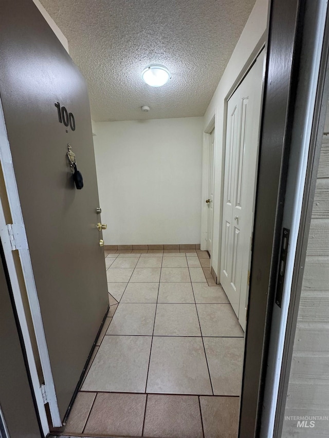 hallway featuring a textured ceiling and light tile patterned floors