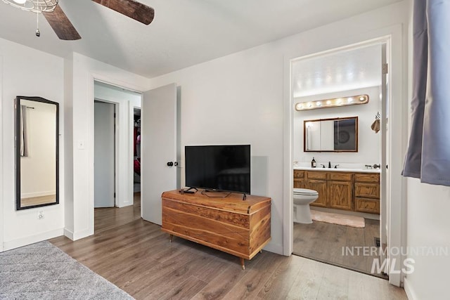 bedroom featuring ceiling fan, wood-type flooring, sink, and ensuite bath