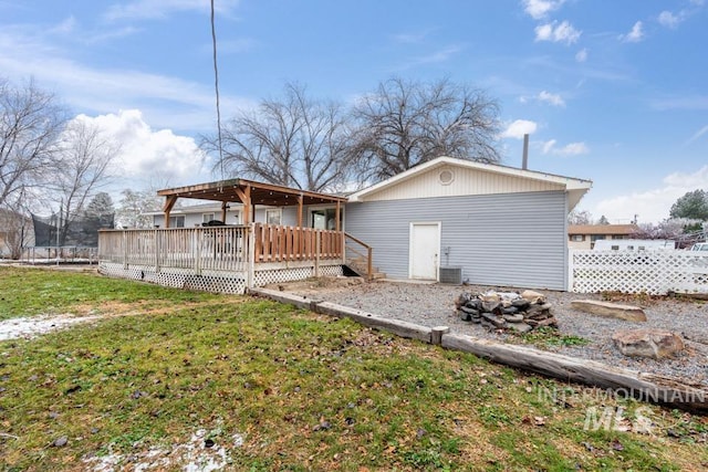 back of property with a wooden deck, a yard, and central AC unit