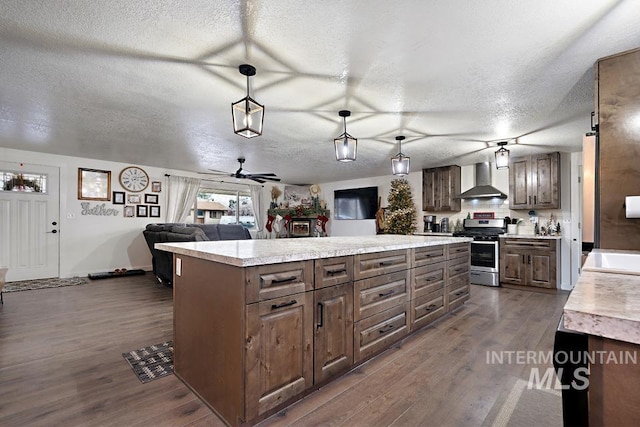 kitchen with hanging light fixtures, wall chimney exhaust hood, a textured ceiling, stainless steel range, and a kitchen island