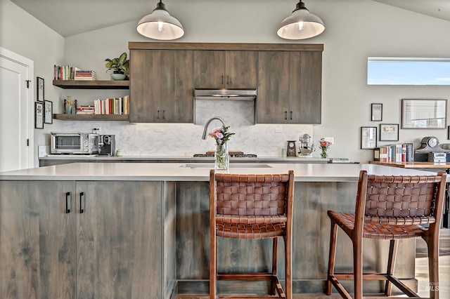 kitchen with vaulted ceiling, a breakfast bar, pendant lighting, and decorative backsplash