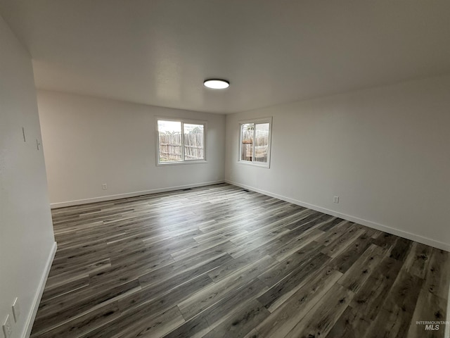 unfurnished room with baseboards and dark wood-type flooring