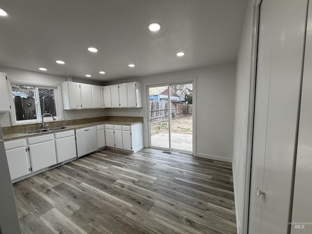 kitchen featuring a sink, wood finished floors, white cabinetry, recessed lighting, and dishwasher