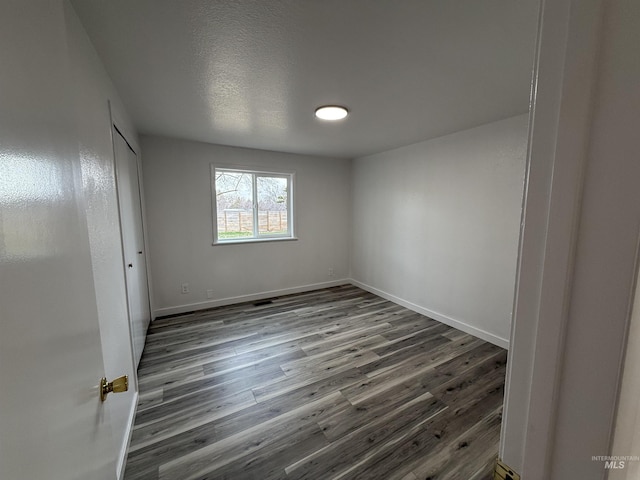 interior space with a closet, a textured ceiling, baseboards, and wood finished floors