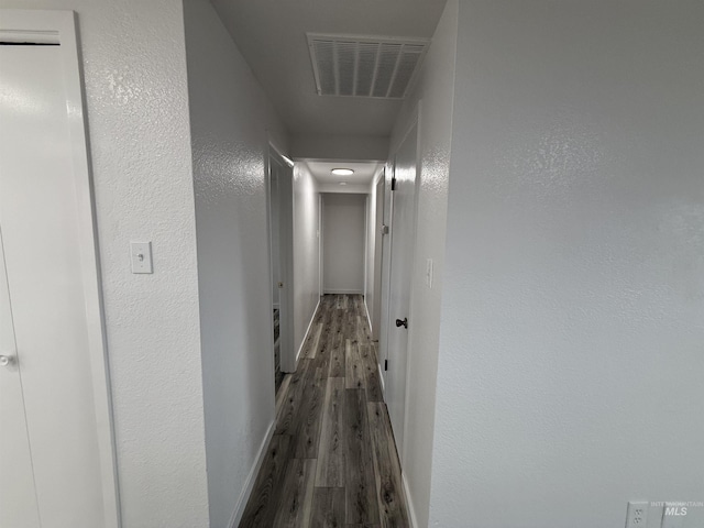 hall with visible vents, baseboards, and wood finished floors