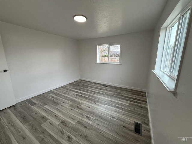 empty room with visible vents, baseboards, and wood finished floors