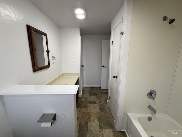 full bath featuring stone finish flooring, baseboards, bathtub / shower combination, and vanity