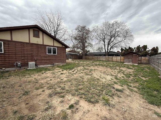 view of yard featuring an outbuilding, central air condition unit, a storage shed, and a fenced backyard