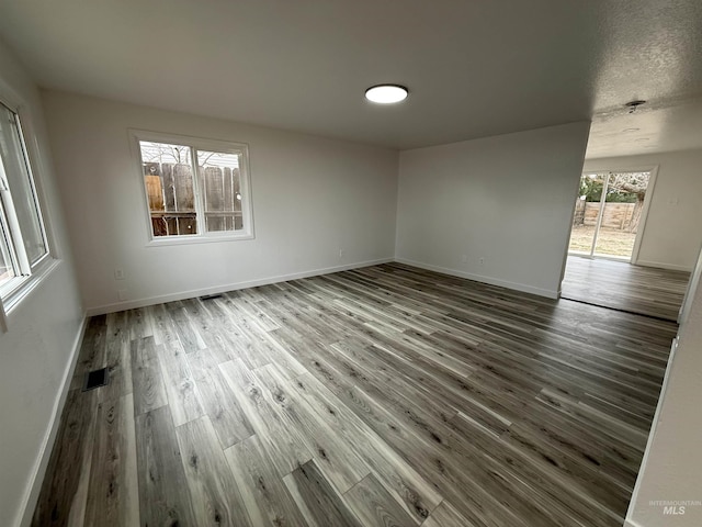 empty room with visible vents, baseboards, and wood finished floors