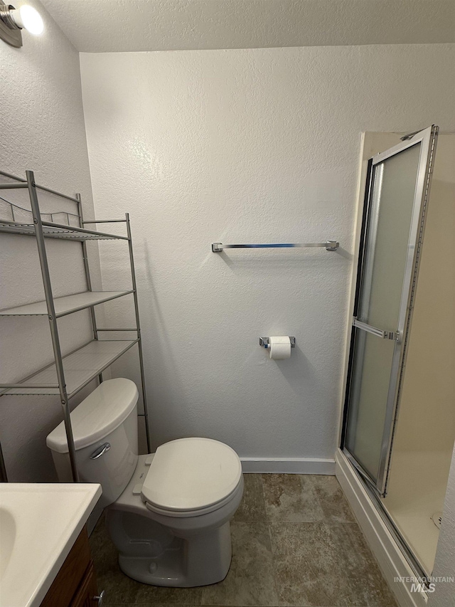 full bath featuring vanity, a shower stall, toilet, and a textured wall