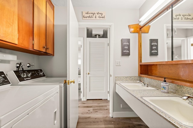 laundry room with washer and dryer, sink, light hardwood / wood-style flooring, and cabinets