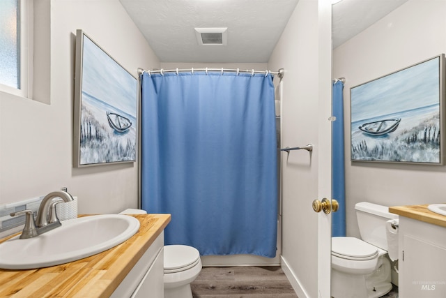 full bathroom featuring toilet, vanity, hardwood / wood-style flooring, a textured ceiling, and shower / tub combo with curtain