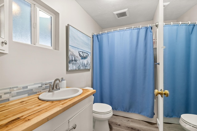 bathroom with toilet, backsplash, hardwood / wood-style floors, and vanity