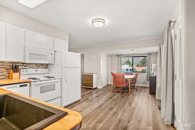 kitchen featuring light wood-type flooring, backsplash, white appliances, and white cabinetry