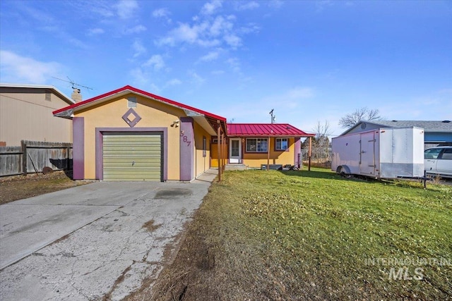 view of front of property featuring driveway, a garage, metal roof, fence, and a front yard