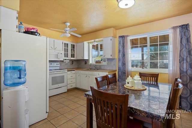 kitchen with tasteful backsplash, white appliances, white cabinets, and light tile patterned floors