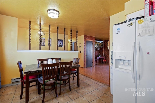 dining area featuring a baseboard radiator, tile patterned flooring, and a textured ceiling