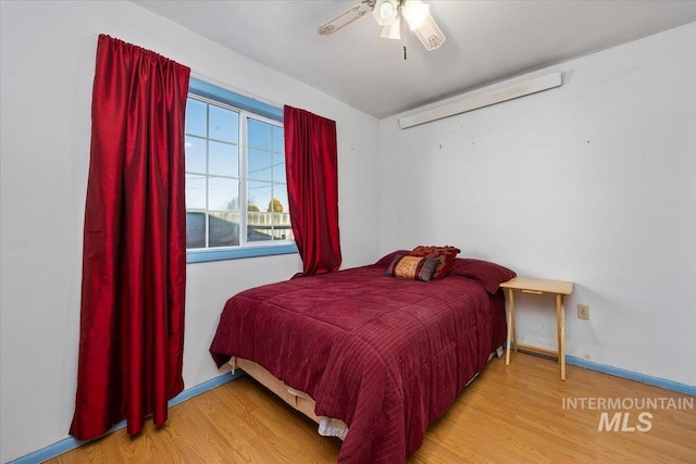 bedroom with ceiling fan, wood finished floors, and baseboards