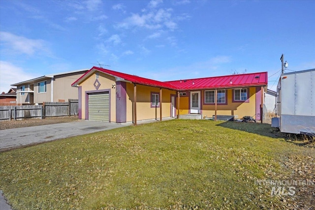 ranch-style home with concrete driveway, fence, metal roof, a garage, and a front lawn