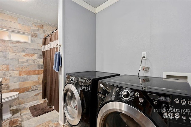 clothes washing area featuring laundry area, ornamental molding, washing machine and dryer, and stone tile floors