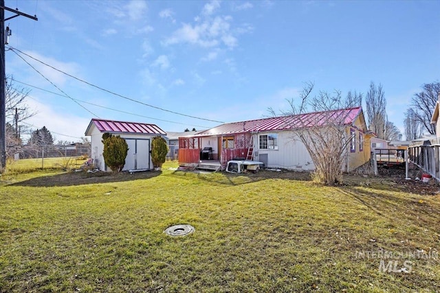 rear view of house with fence, a storage unit, an outdoor structure, and a yard