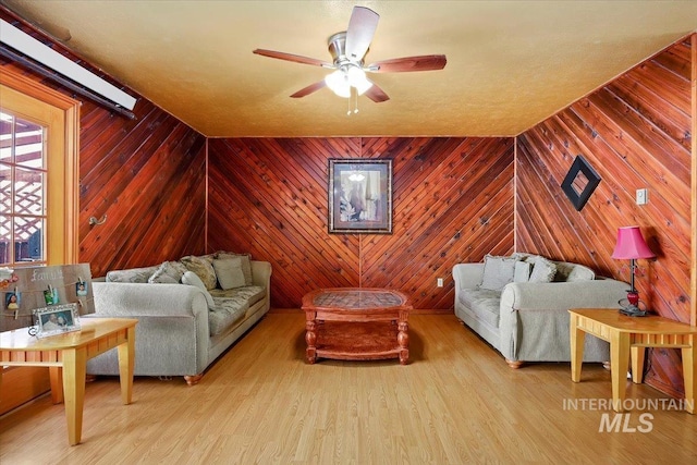 interior space featuring wood walls, a ceiling fan, and wood finished floors