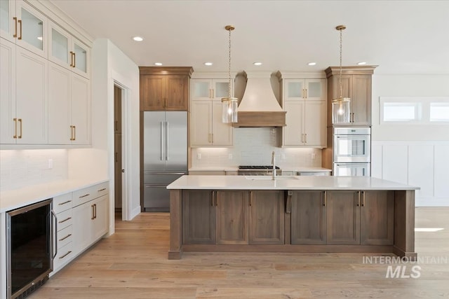 kitchen with pendant lighting, custom exhaust hood, beverage cooler, and stainless steel built in fridge