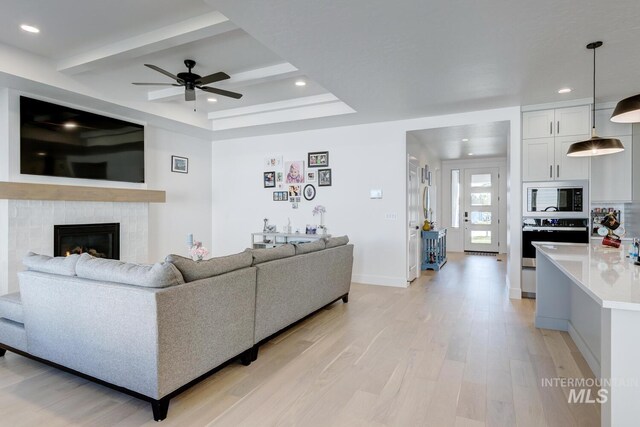 3661 S Corabell Way, Meridian, ID 83642 - living room with light wood-style floors, a ceiling fan, recessed lighting, baseboards, and a glass covered fireplace