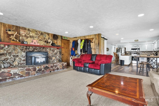 living area with wood walls, a barn door, a textured ceiling, and recessed lighting