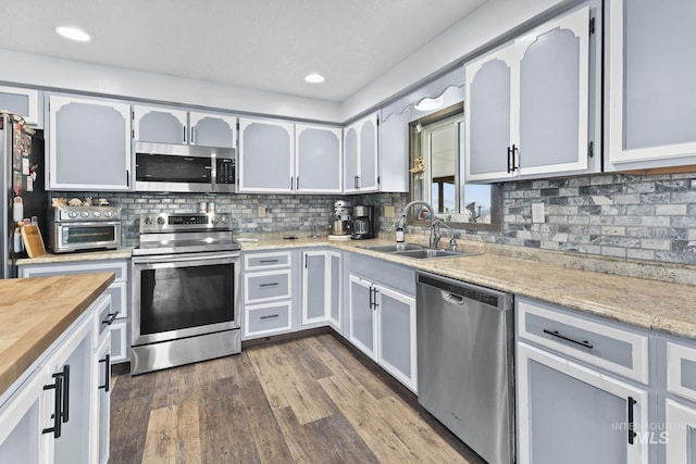 kitchen featuring stainless steel appliances, tasteful backsplash, dark wood-style flooring, and a sink