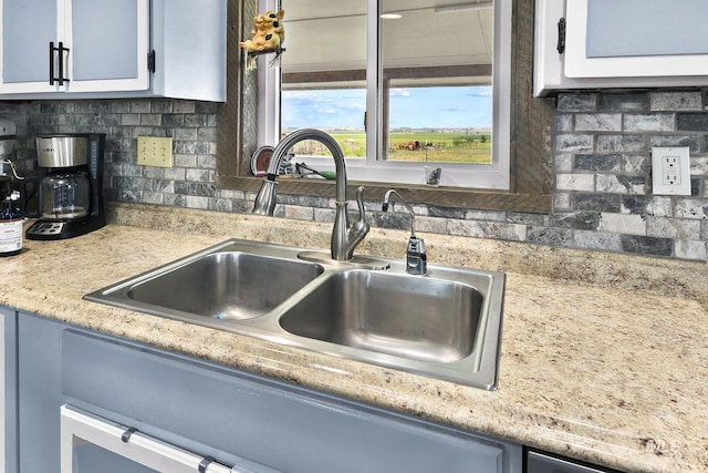 kitchen featuring white cabinetry, backsplash, a sink, and light countertops