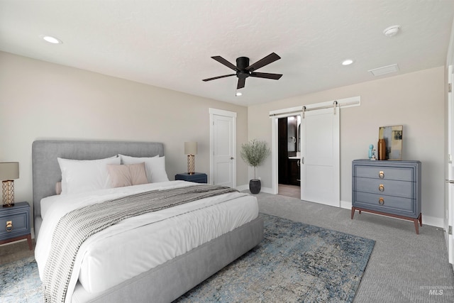 carpeted bedroom featuring a barn door and ceiling fan