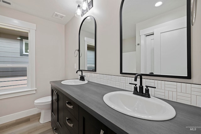 bathroom with hardwood / wood-style floors, vanity, tasteful backsplash, and toilet