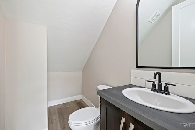 bathroom with vanity, hardwood / wood-style flooring, toilet, and vaulted ceiling