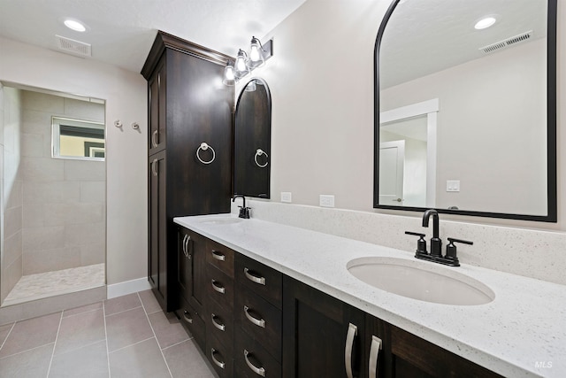 bathroom with tile patterned flooring, vanity, and tiled shower