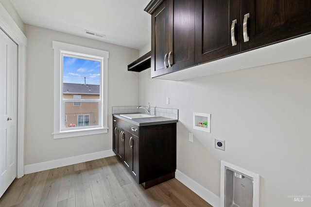 clothes washing area with cabinets, light hardwood / wood-style floors, sink, washer hookup, and electric dryer hookup