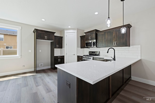 kitchen with stainless steel appliances, hardwood / wood-style flooring, hanging light fixtures, and sink