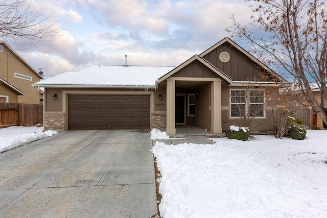 view of front of home with a garage, brick siding, fence, driveway, and board and batten siding