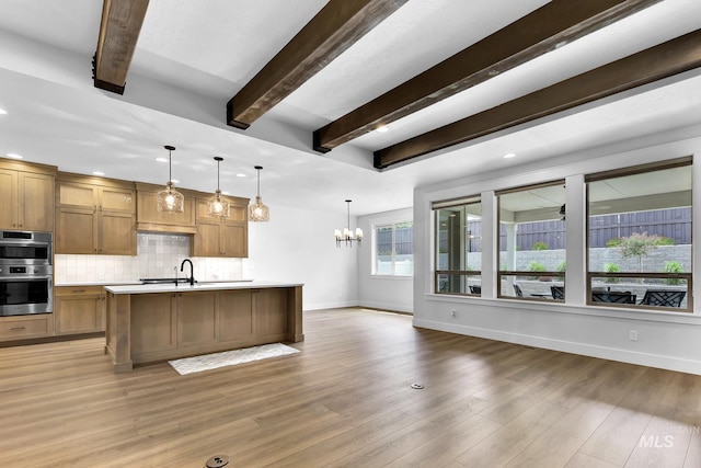 2499 E Berghan Ln, Meridian, ID 83642 - kitchen with light countertops, baseboards, tasteful backsplash, a kitchen island with sink, and a chandelier