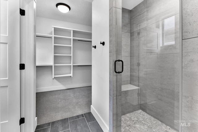 2499 E Berghan Ln, Meridian, ID 83642 - full bathroom featuring a shower stall, a walk in closet, baseboards, and tile patterned floors